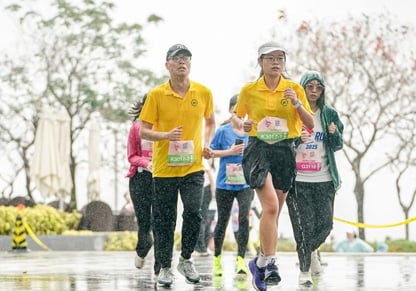 A man and a woman run in the rain wearing yellow Intertek t-shirts.