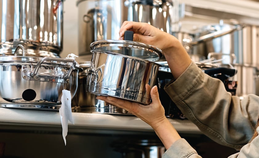 Young happy woman buying new cooking pot in the supermarket. Copy space.