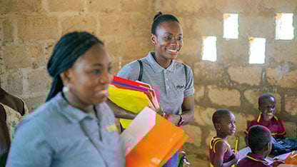 Two Intertek volunteers smiling while in a classroom with young children