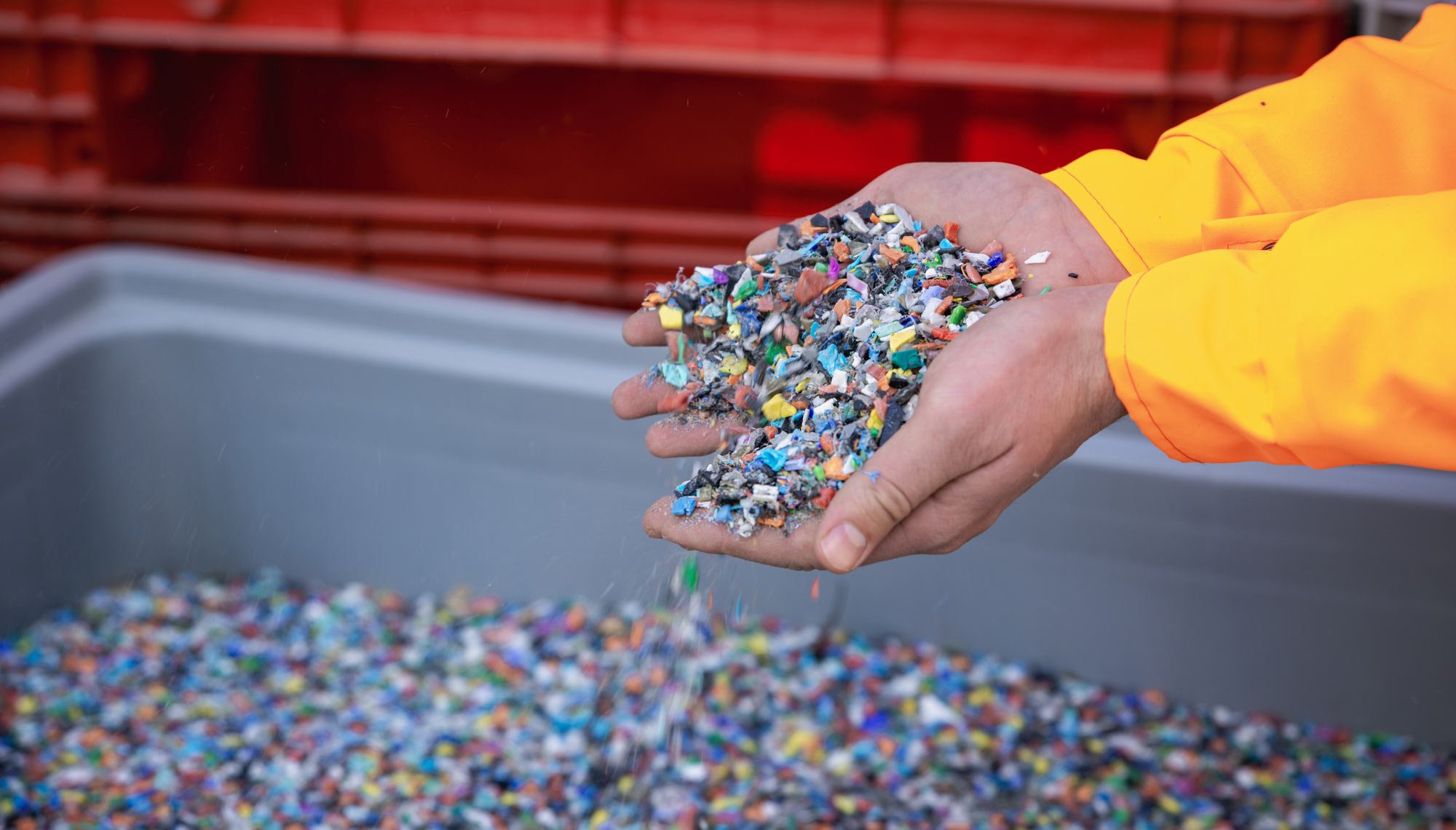 Open hands holding a scoop of loose plastic resin pellets