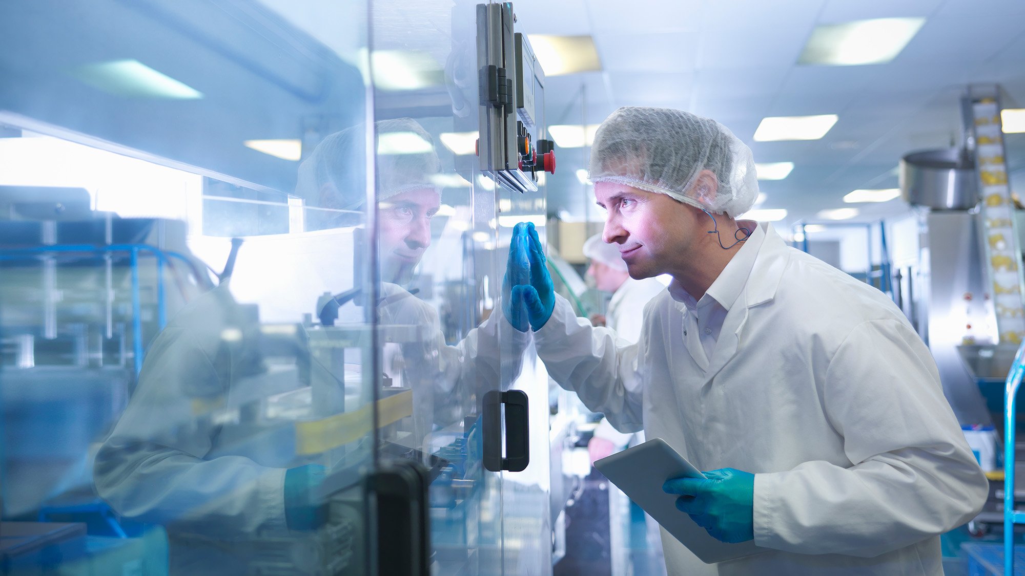 Worker inspecting tablets as they are put into packaging in pharmaceutical factory