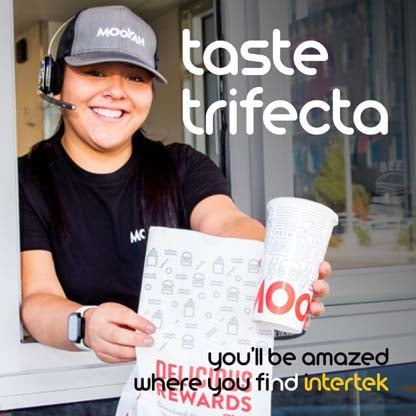 A restaurant employee handing bagged food out of a drive-up window