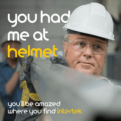 Two men carrying a large pipe while wearing safety helmets