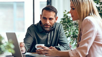 Man and woman looking at laptop at a table